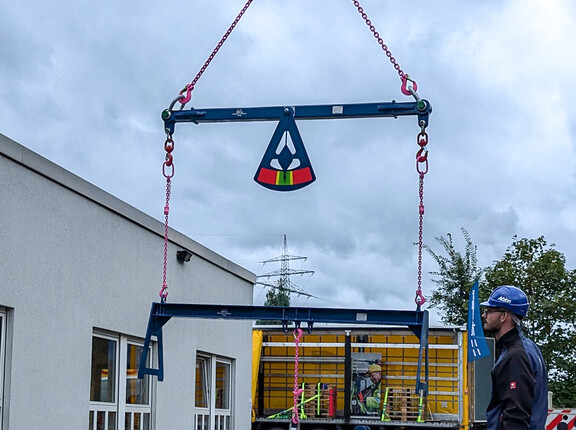 Eine Traverse mit Gewicht im Lot, daneben ein Mann mit Schutzkleidung.